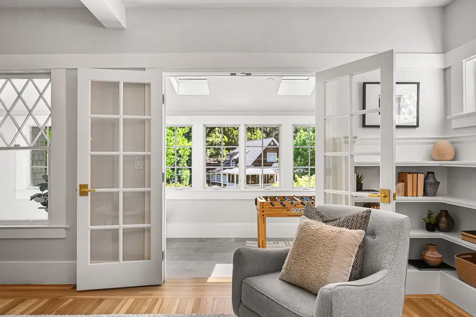 French doors opening to a sunroom with windows on three sides